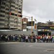 People wait in line to board a bus in Caracas, Venezuela on March 14, 2019