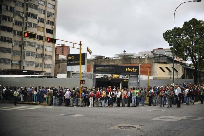 People wait in line to board a bus in Caracas, Venezuela on March 14, 2019