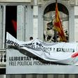 A banner reading "Free political prisoners and those exiled" bearing a white ribbon with a red brush stroke replaces an older one bearing a yellow ribbon on the balcony of the regional government's headquarters in Barcelona