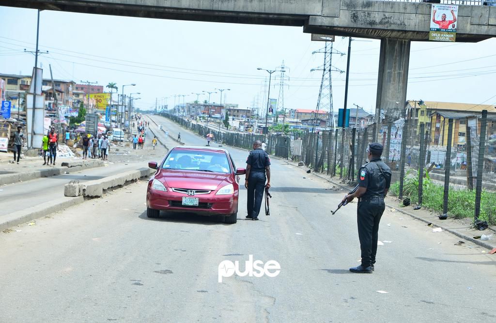 Nigerian police officers stop a car at a checkpoint in Mile 12 (Pulse)