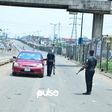 Nigerian police officers stop a car at a checkpoint in Mile 12 (Pulse)