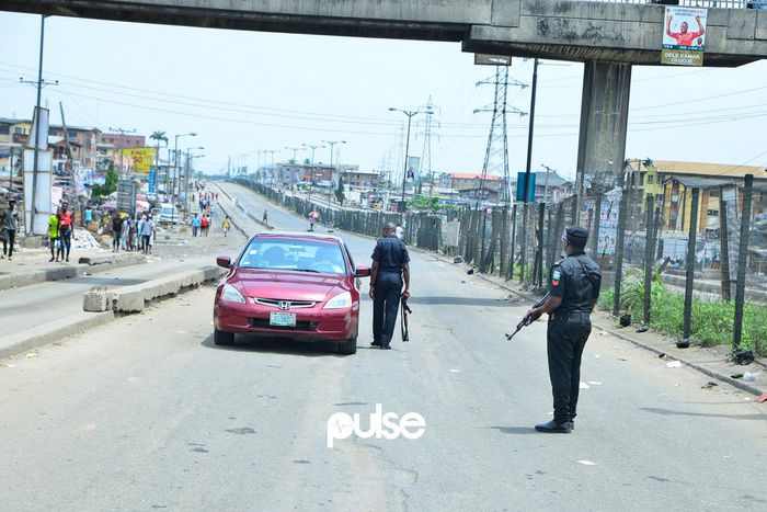 Nigerian police officers stop a car at a checkpoint in Mile 12 (Pulse)