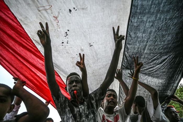 Sudanese protesters shout slogans and flash victory signs during a rally outside the army complex in Sudan's capital Khartoum
