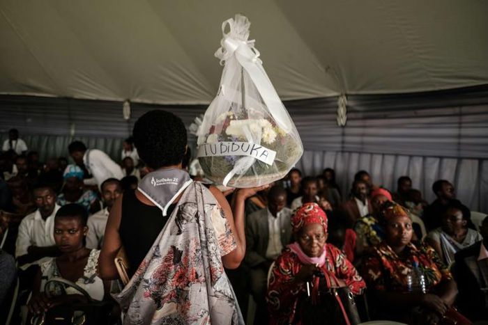 A woman carries flowers to offer before the mass funeral to bury 81 coffins containing newly discoverd remains of 84,437 victims of the 1994 genocide in the mass grave at the Nyanza Genocide Memorial, suburb of the capital Kigali, on May 4, 2019. The r...