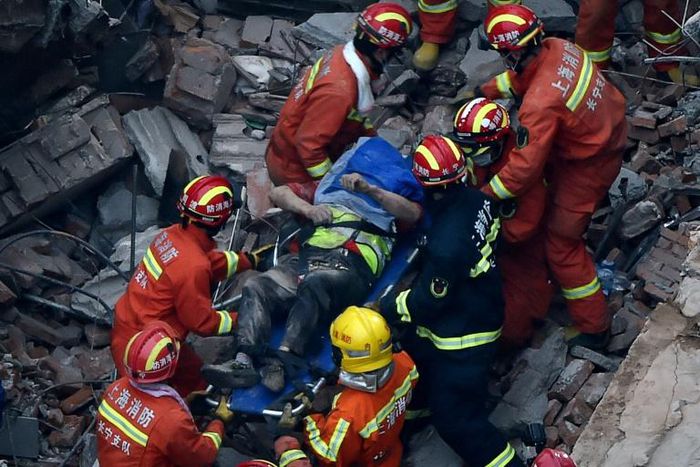 About half of the low-rise building collapsed in Shanghai, crushing construction workers under piles of toppled concrete pillars and shattered wooden beams