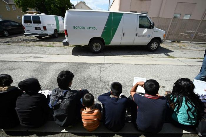Central American asylum seekers sit outside the bus station in San Bernardino, California