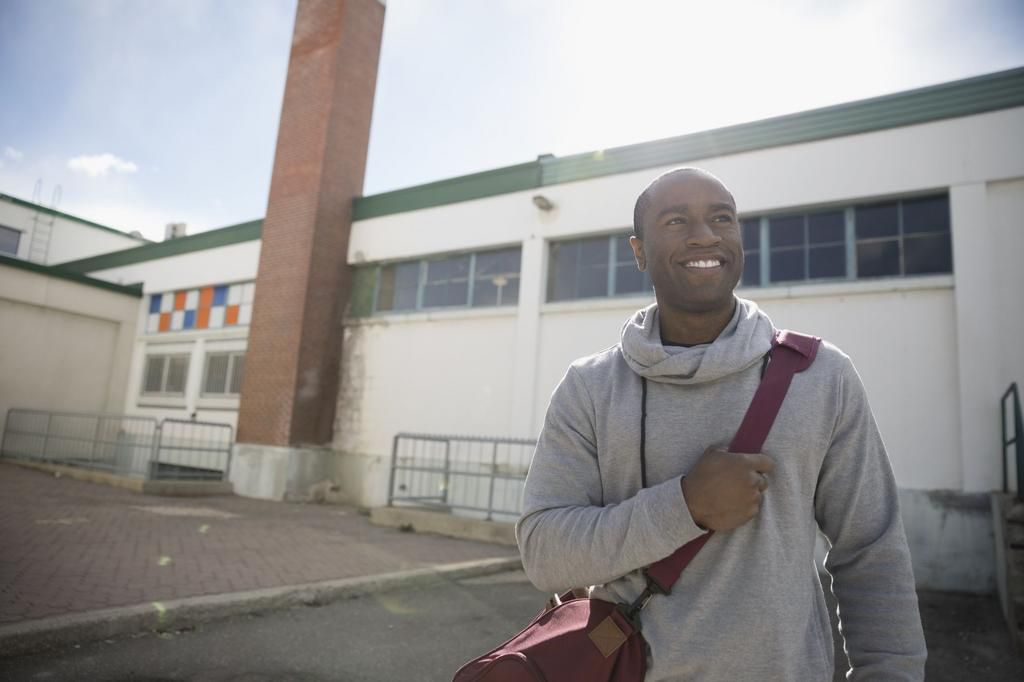 Confident, smiling man with gym bag in parking lot post workout