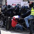Police deal with a marcher draped in the French flag, before the May Day rally got underway in Paris