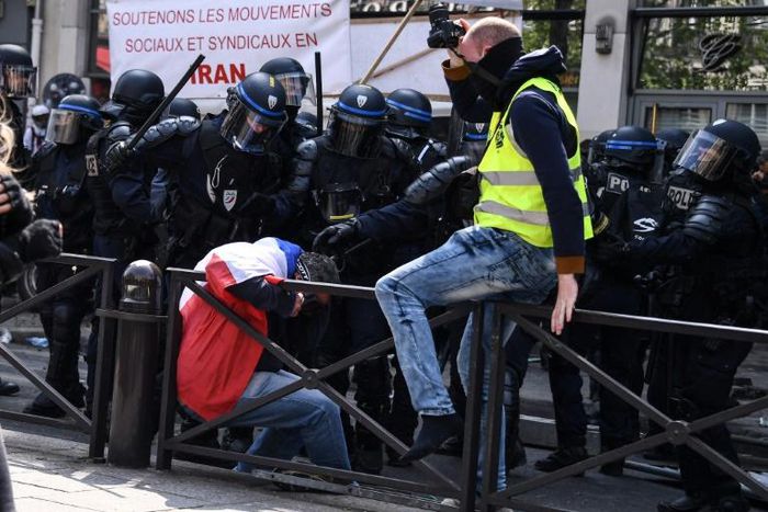 Police deal with a marcher draped in the French flag, before the May Day rally got underway in Paris