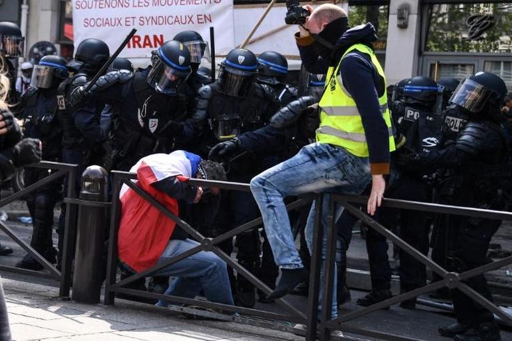 Police deal with a marcher draped in the French flag, before the May Day rally got underway in Paris
