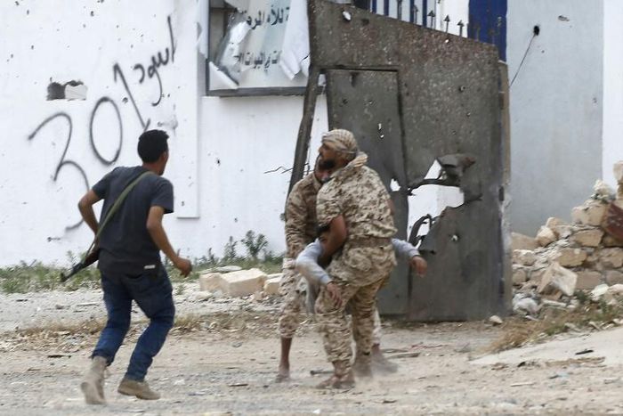 Fighters loyal to Libya's Government of National Accord carry a wounded man, as clashes rage south of the capital Tripoli
