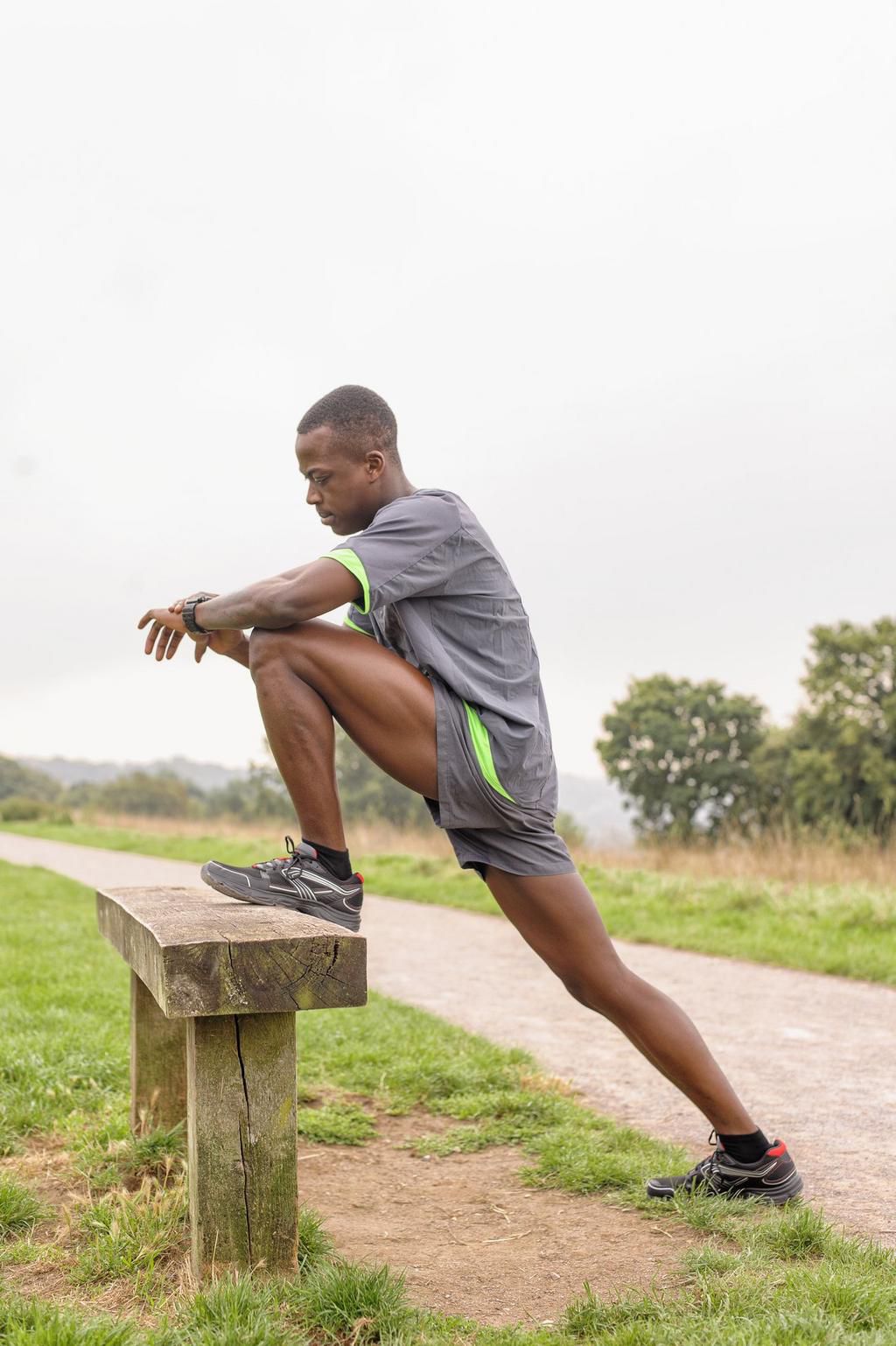 African American runner stretching on park bench