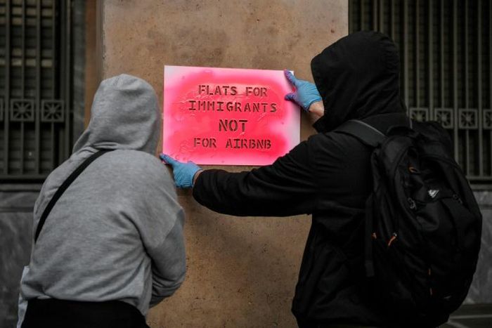 Activists stencil a slogan reading "Flats for immigrants not for Airbnb" on a wall during a demonstration outside the EU offices in central Athens