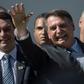 Brazilian President Jair Bolsonaro (R) waves next to his son Flavio, a federal senator who denies any impropriety after a report that he allegedly made more than three million reais ($790,000) buying and selling 19 apartments and commercial locations i...