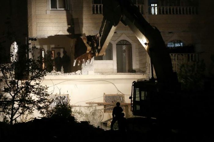 Israeli forces use a bulldozer to destroy two apartments that were home to the family of a Palestinian accused of the February killing of an Israeli woman in a pre-dawn operation in the flashpoint West Bank city of Hebron