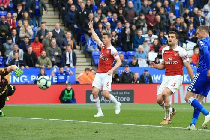 Jamie Vardy (R) slots the ball past Arsenal goalkeeper Bernd Leno (L) to complete a 3-0 win for Leicester
