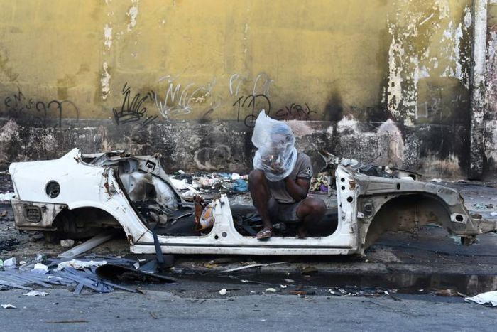 The Mare favela in Rio de Janeiro is notorious for the heavy influence of drug traffickers -- here, a resident smokes crack beside the shell of a disused and burnt out car there