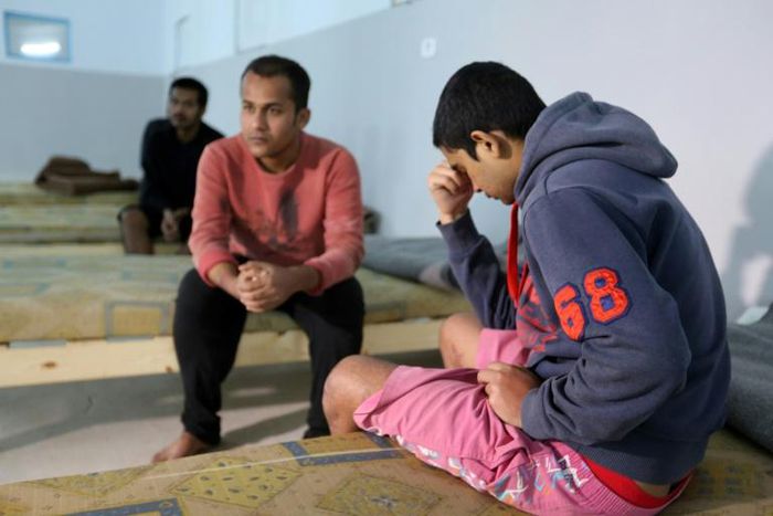 Survivors of a migrants shipwreck that killed around 60 people sit in a Tunisian shelter after being rescued at sea