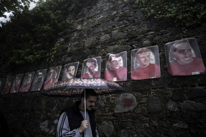 A man walks near posters of Grande Torino's football players on the Superga hill in Turin.