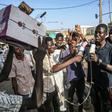 Young Sudanese protesters mimic journalists -- complete with a cardboard mocked up camera and a plastic bottle to represent a microphone -- to poke fun at state TV for failing to cover demonstrations