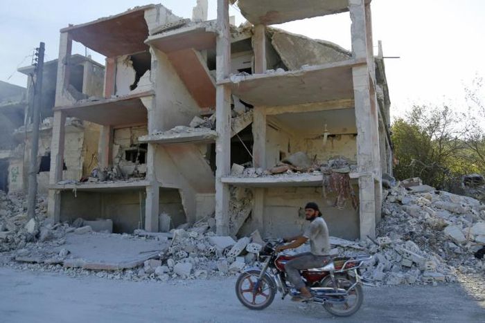A man rides a motorcycle past a destroyed building in an area that was hit by a reported air strike in the district of Jisr al-Shughur, in the Syrian province of Idlib, on September 4, 2018
