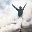 A protester raises his arms as French anti-riot police fire teargas as hardline anti-capitalist elements join Paris' annual May Day rally