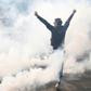 A protester raises his arms as French anti-riot police fire teargas as hardline anti-capitalist elements join Paris' annual May Day rally