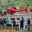 People watch as an injured person is carried onto a rescue helicopter after two buildings collapsed in Muzema, Rio de Janeiro, Brazil