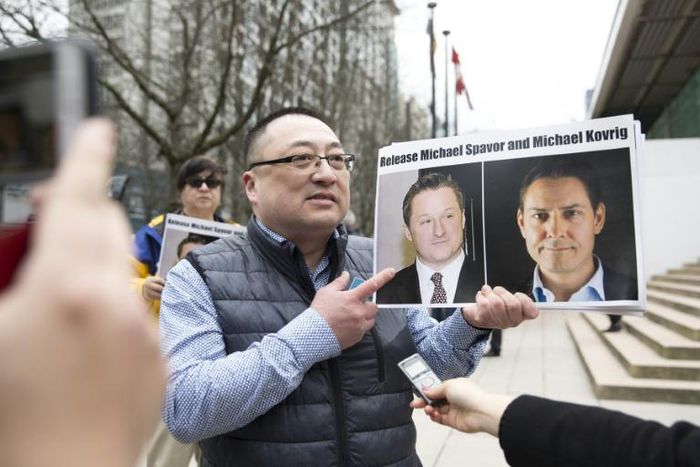 Louis Huang of Vancouver Freedom and Democracy for China holding photos of Canadians Michael Spavor and Michael Kovrig