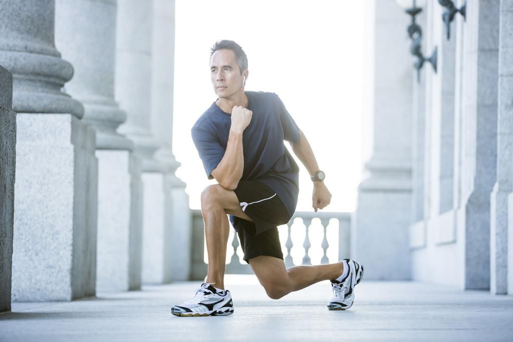Mixed race man stretching outside courthouse