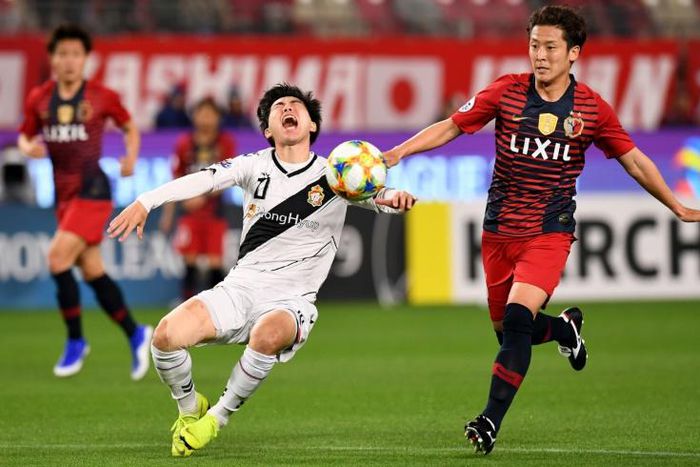 Gyeongnam forward Kim Seung-jun (white shirt) left is brought down by Kashima midfielder Ryota Nagaki