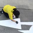 A Thailand Post employee repaints a street sign outside her office ahead of King Maha Vajiralongkorn's coronation