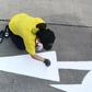 A Thailand Post employee repaints a street sign outside her office ahead of King Maha Vajiralongkorn's coronation