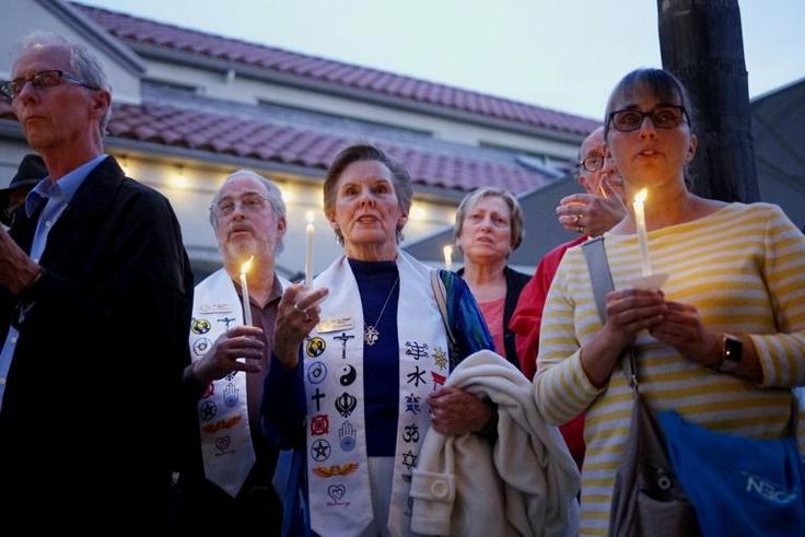 People hold a candlelight vigil for victims of the attack on a synagogue in California