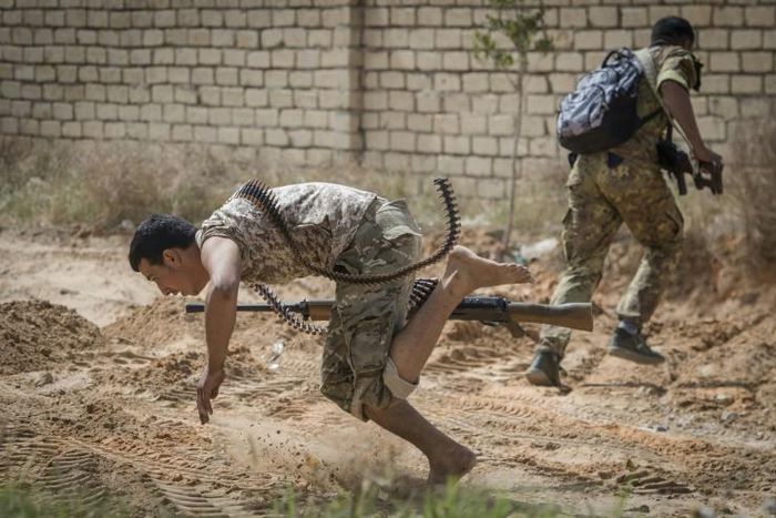 Fighters loyal to the internationally recognised Government of National Accord run for cover during clashes with forces loyal to strongman Khalifa Haftar south of the Tripoli suburb of Ain Zara