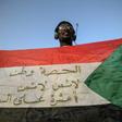 A protester flashes a Sudanese flag covered with patriotic slogans outside army headquarters in Khartoum