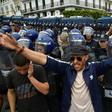 Algerian security forces stand guard behind protesters in the capital Algiers on Friday