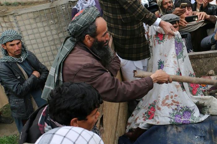 In this picture taken on March 23, 2019 Afghan men uncover the dead bodies of young children laying in the back of a truck, after being killed in an air strike in Kunduz Province.At least 13 civilians were killed, mostly children, in an air strike by "...