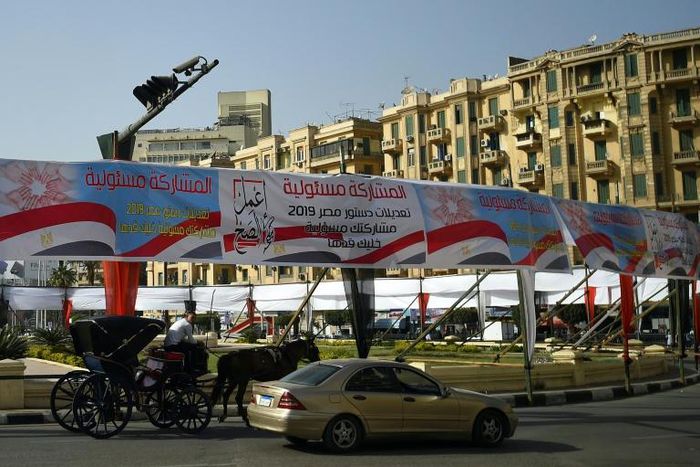 Egyptians pass under banners reading in Arabic "Do what is right", and "Participation is your responsibility", urging voters to participate in a referendum on constitutional amendments