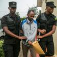 Callixte Nsabimana, spokesman for the National Liberation Front (FLN), was escorted by police officers into the court in Kigali