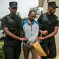 Callixte Nsabimana, spokesman for the National Liberation Front (FLN), was escorted by police officers into the court in Kigali
