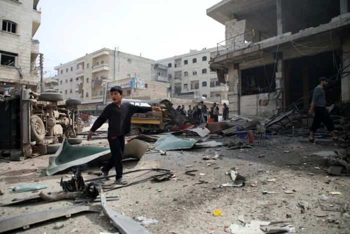 Residents walk among debirs caused by the reported explosion of a booby-trapped motorcycle in the city of al-Dana in Syria's rebel-held Idlib region, on the border with Turkey, on April 27, 2019.