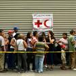 People queue to receive water drums and water purification tablets from the Red Cross in Caracas, Venezuela, on April 16, 2019, after the first shipment of Red Cross humanitarian aid arrived by plane from Panama
