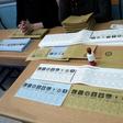 Election official sit next to voting ballots displayed on a table at a polling station during local elections in Istanbul on March 31, 2019
