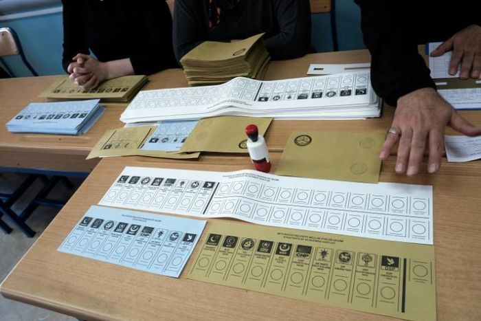 Election official sit next to voting ballots displayed on a table at a polling station during local elections in Istanbul on March 31, 2019