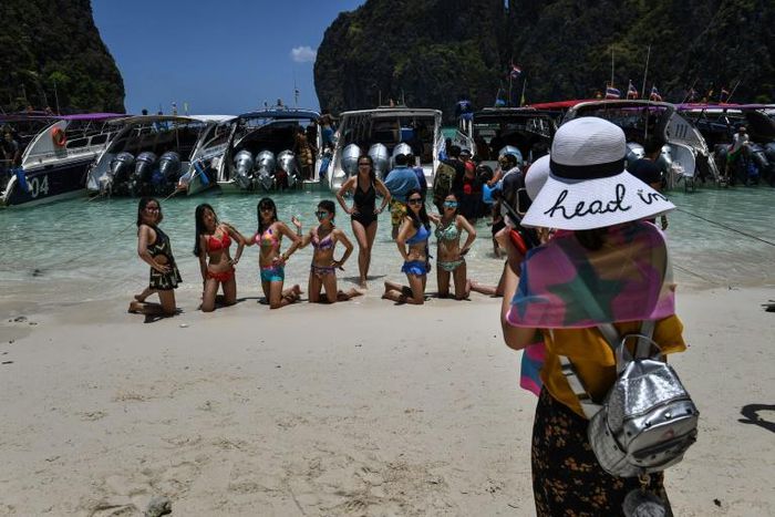 Tourists pose in Maya Bay before a row of boats in April 2018, shortly before the beach was ruled off-limits in a bid to protect the environment