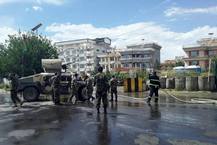 Afghan security personnel and firefighters clean the site of a suicide attack near the Marshal Fahim Military Academy base in Kabul