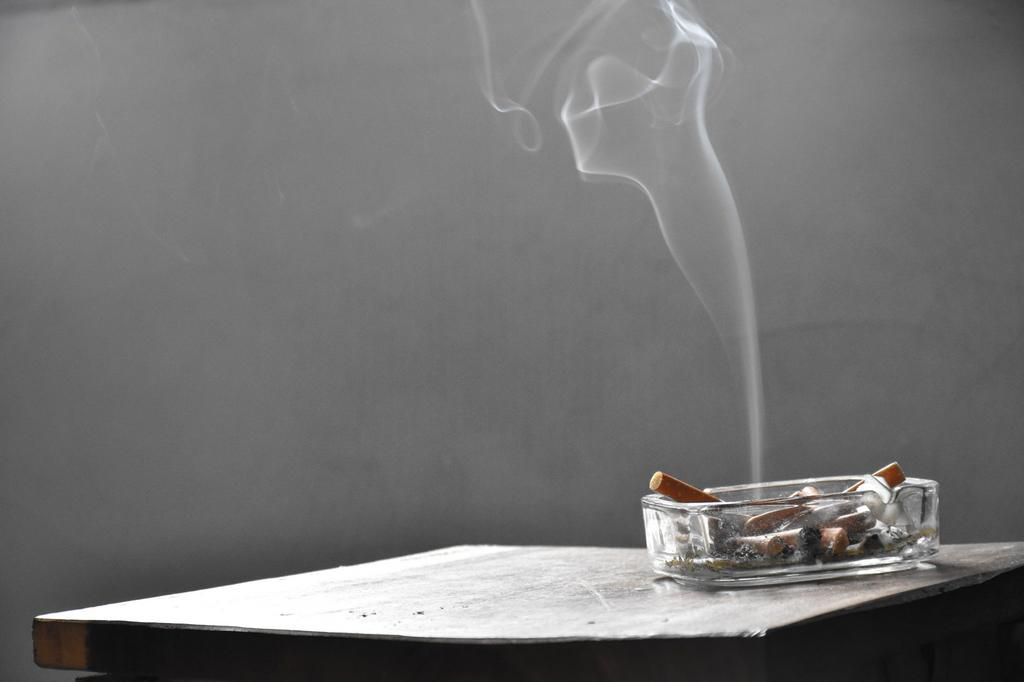 Close-Up Of Smoke Emitting From Cigarette Butt In Ashtray On Table