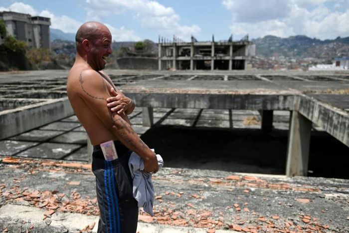 Venezuelan Erick Hurtado, with Bolivar bills equivalent to less than a US dollar tucked into his waistband, stands on the roof of Jehovah Gire, a half-done building in the Petare neighborhood of Caracas that is now home to dozens of squatters