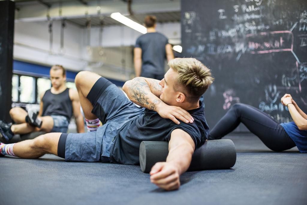 Man rolling on foam roller at health club